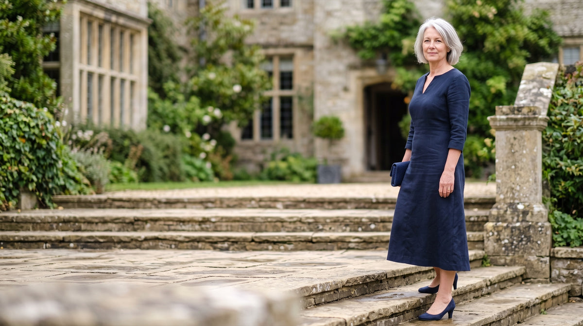 Woman in her late fifties in a navy dress with three-quarter sleeves on the steps of a wedding venue